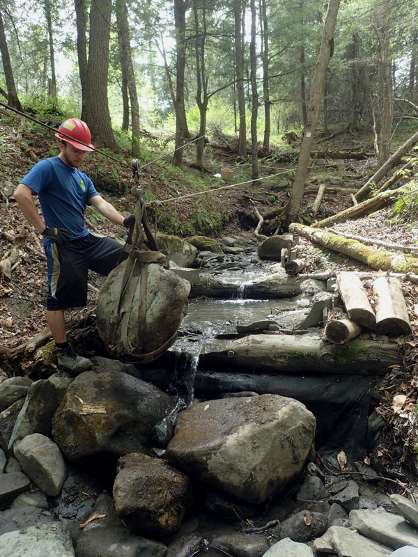 adding a rock to erosion control dam